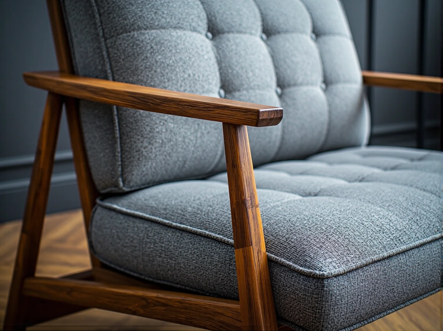 Szary fotel retro z pikowaną tapicerką i drewnianymi podłokietnikami