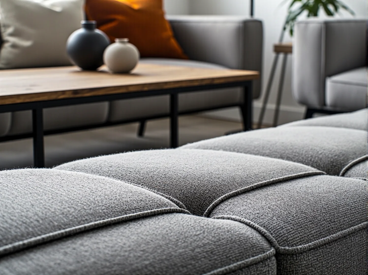 Szara sofa tapicerowana z pikowanym siedziskiem z tkaniny